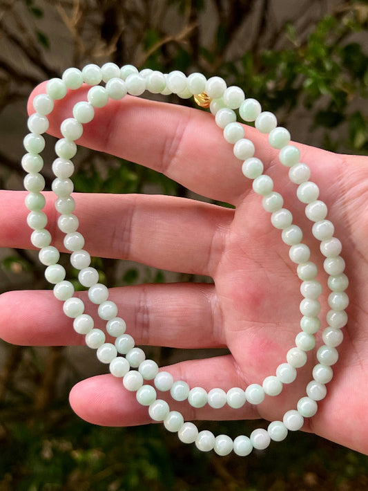Close-up of 6mm Certified Grade A Burmese jadeite beads featuring beautiful icy imperial white and apple green hues, item JN006