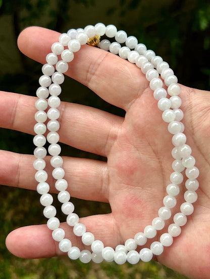 Close-up of 6.2mm Certified Grade A Burmese jadeite beads featuring beautiful icy milky white and light apple green hues, item JN017