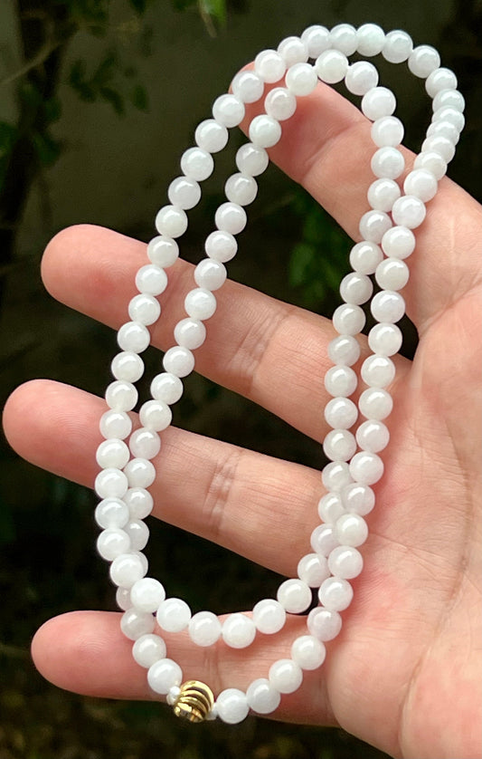 Close-up of 6.3mm Certified Grade A Burmese jadeite beads featuring beautiful icy milky white and light apple green hues, item JN016