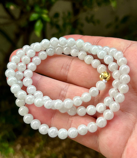 Close-up of 6.8mm Certified Grade A Burmese jadeite beads featuring beautiful icy milky white and light apple green hues, item JN012