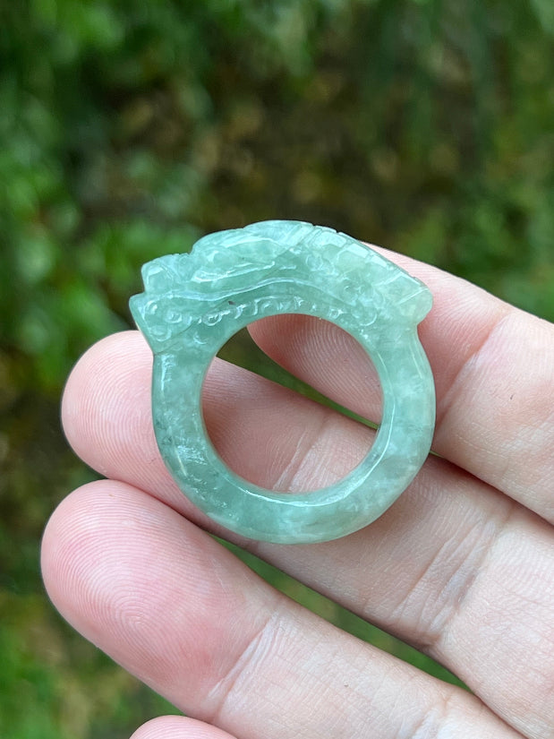 Hand holding a Size US 9.75 certified Grade A Burmese jadeite ring featuring a detailed hand-carved dragon motif in icy green, item JDR009
