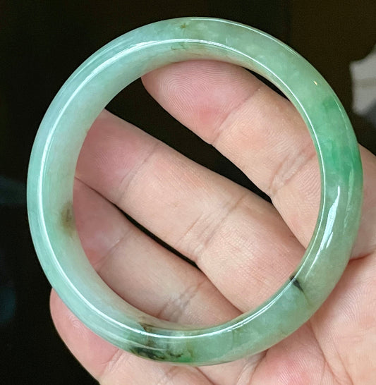 Hand holding a 58.6mm certified Grade A Burmese jadeite bangle in icy light bluish milky white with imperial & apple green and honey hues, item JB120