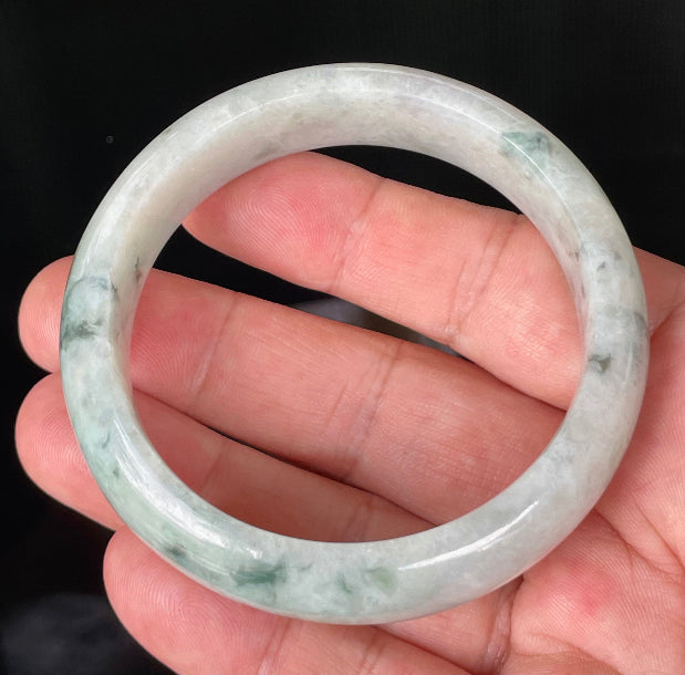 Hand holding a 58.4mm certified Grade A Burmese jadeite bangle in greyish milky white with apple and imperial green hues, item JB831