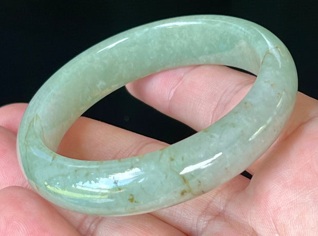 Close-up of fine crystalline texture and honey hues on icy apple green jadeite bangle