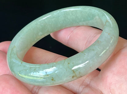Close-up of fine crystalline texture and honey hues on icy apple green jadeite bangle