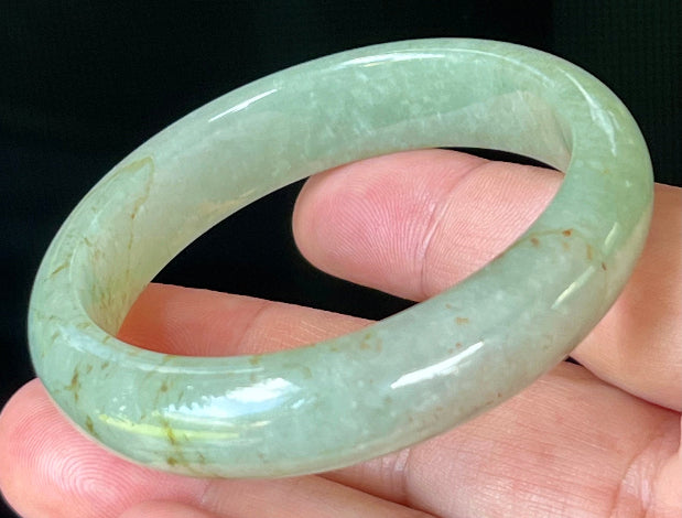 Close-up of fine crystalline texture and honey hues on icy apple green jadeite bangle