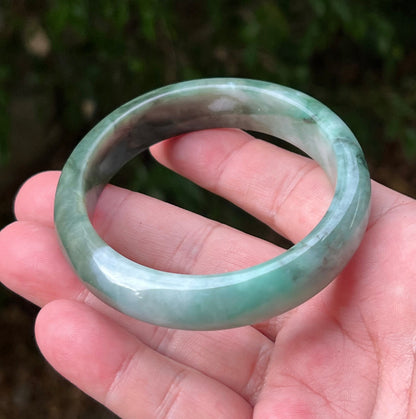 Close-up of moss in snow and blue green patterns on icy green jadeite bangle
