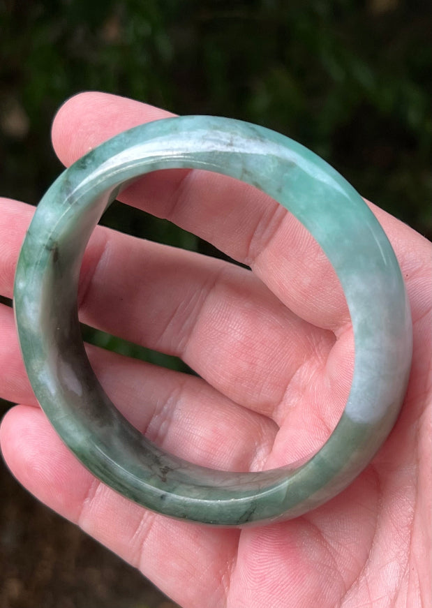 Close-up of moss in snow and blue green patterns on icy green jadeite bangle
