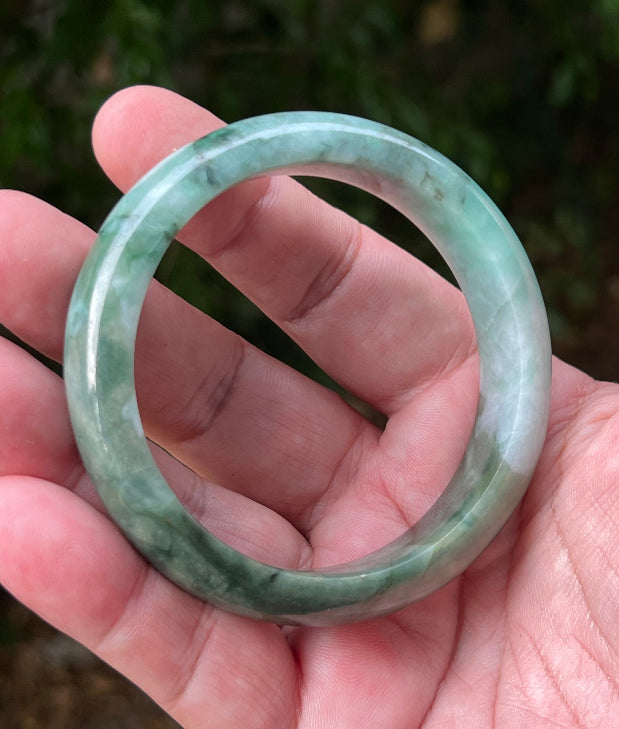 Close-up of moss in snow and blue green patterns on icy green jadeite bangle