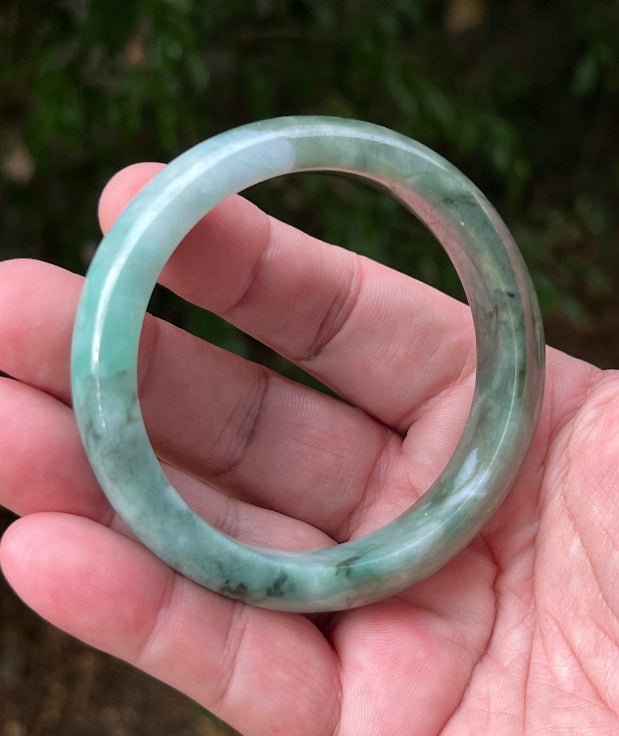 Close-up of moss in snow and blue green patterns on icy green jadeite bangle
