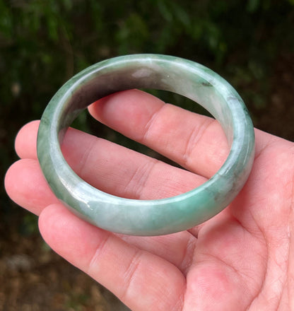 Close-up of moss in snow and blue green patterns on icy green jadeite bangle