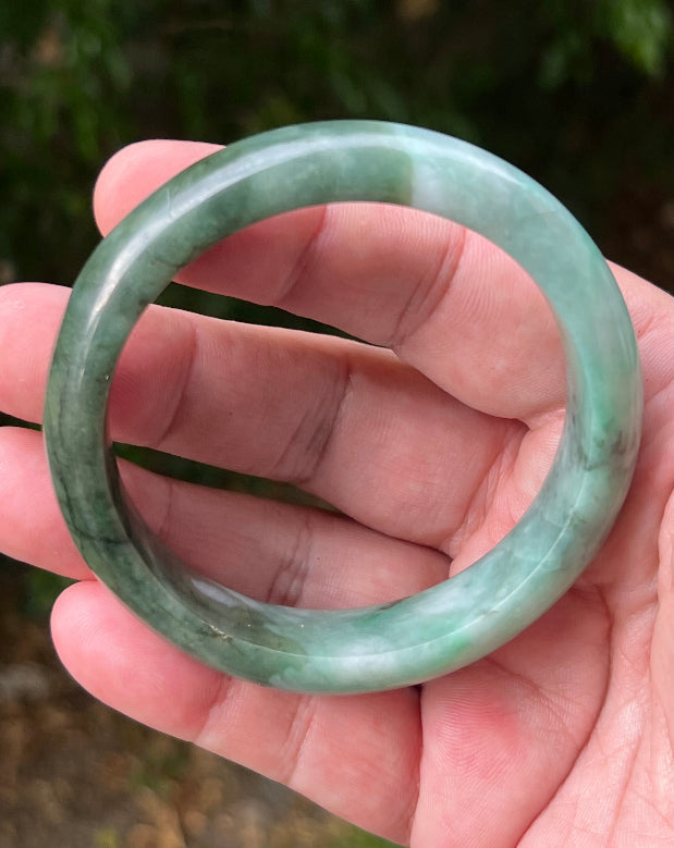 Close-up of moss in snow and blue green patterns on icy green jadeite bangle