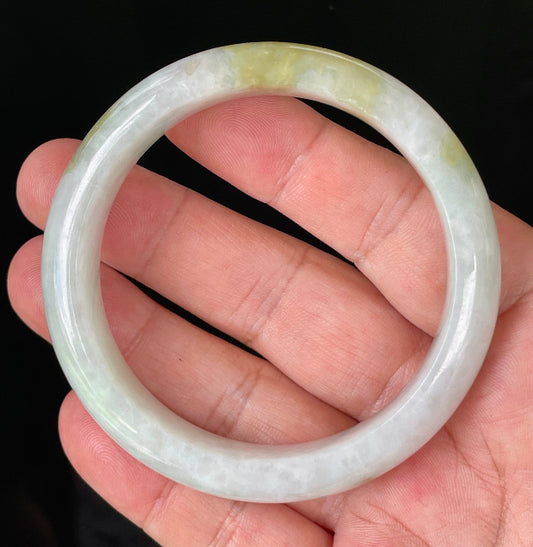Hand holding a 58.4mm certified Grade A Burmese jadeite bangle in icy greyish milky white with apple and forest green hues, item JB851