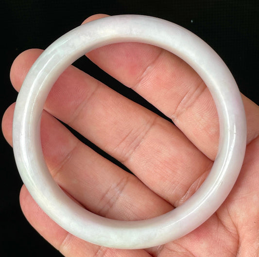 Hand holding a 58.5mm certified Grade A Burmese jadeite bangle in icy milky white with light lavender and apple green hues, item JB829