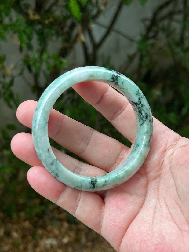 Close-up of moss and snowflake green patterns on icy white jadeite bangle