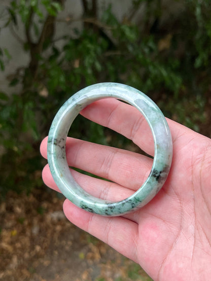 Close-up of moss and snowflake green patterns on icy white jadeite bangle