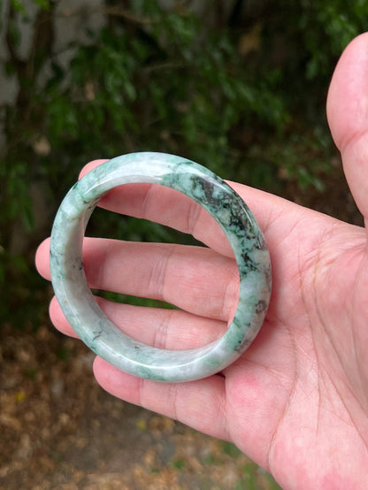Close-up of moss and snowflake green patterns on icy white jadeite bangle