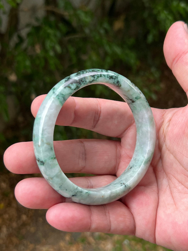 Close-up of moss and snowflake green patterns on icy white jadeite bangle