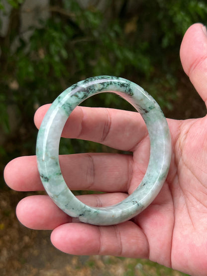 Close-up of moss and snowflake green patterns on icy white jadeite bangle