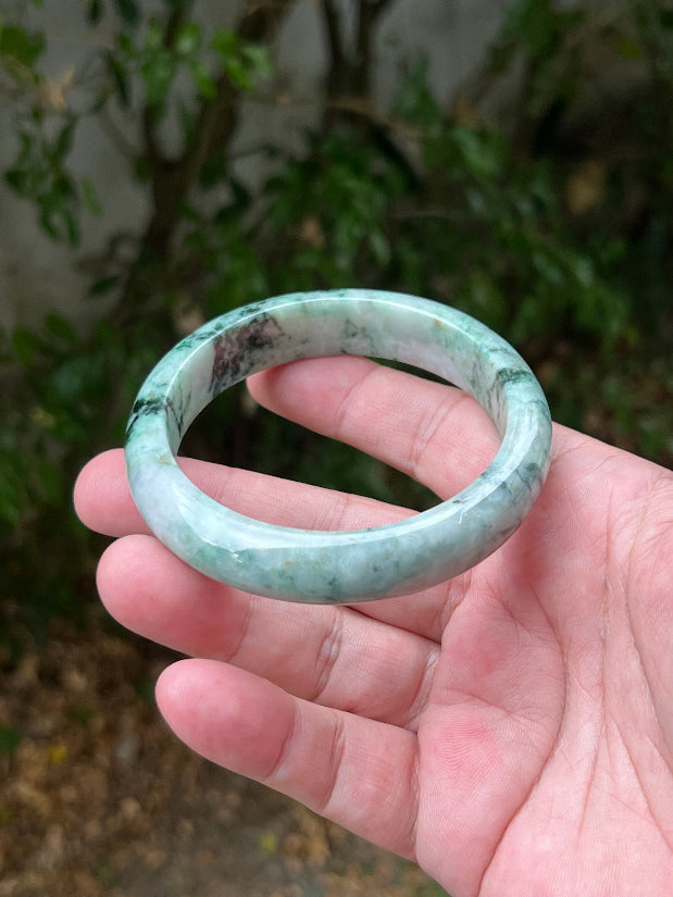 Close-up of moss and snowflake green patterns on icy white jadeite bangle
