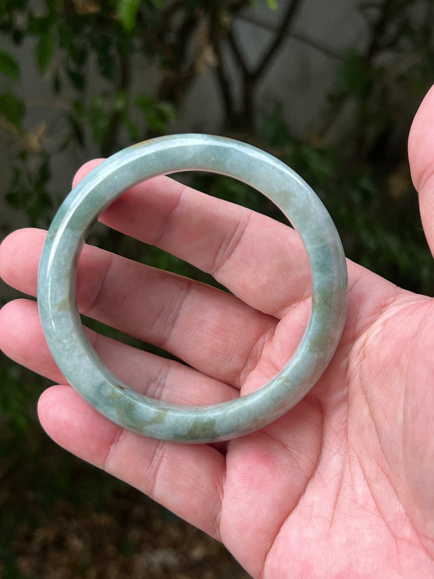 Close-up of natural moss green cloud formations on icy seafoam jadeite bangle