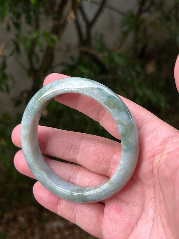 Close-up of natural moss green cloud formations on icy seafoam jadeite bangle