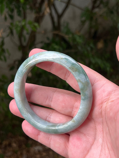 Close-up of natural moss green cloud formations on icy seafoam jadeite bangle