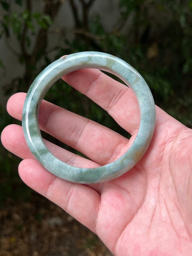 Close-up of natural moss green cloud formations on icy seafoam jadeite bangle
