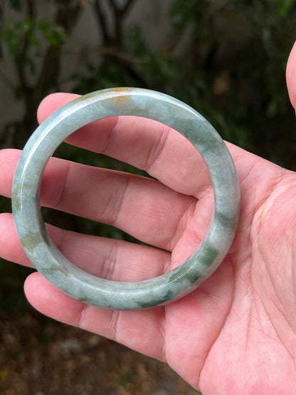 Close-up of natural moss green cloud formations on icy seafoam jadeite bangle
