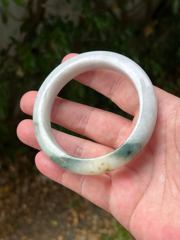 Close-up of soft green and honey patterns on icy white jadeite bangle