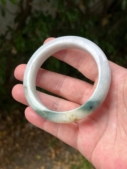 Close-up of soft green and honey patterns on icy white jadeite bangle