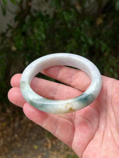 Close-up of soft green and honey patterns on icy white jadeite bangle