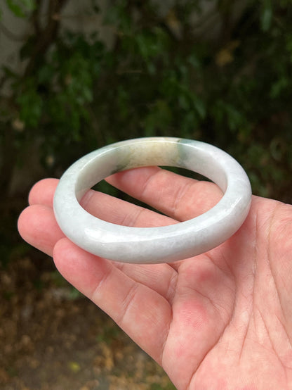 Close-up of soft green and honey patterns on icy white jadeite bangle