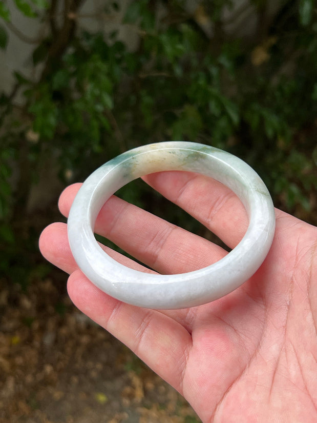 Close-up of soft green and honey patterns on icy white jadeite bangle