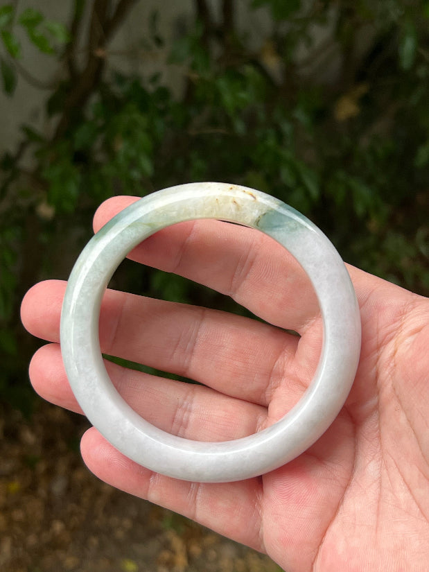 Close-up of soft green and honey patterns on icy white jadeite bangle