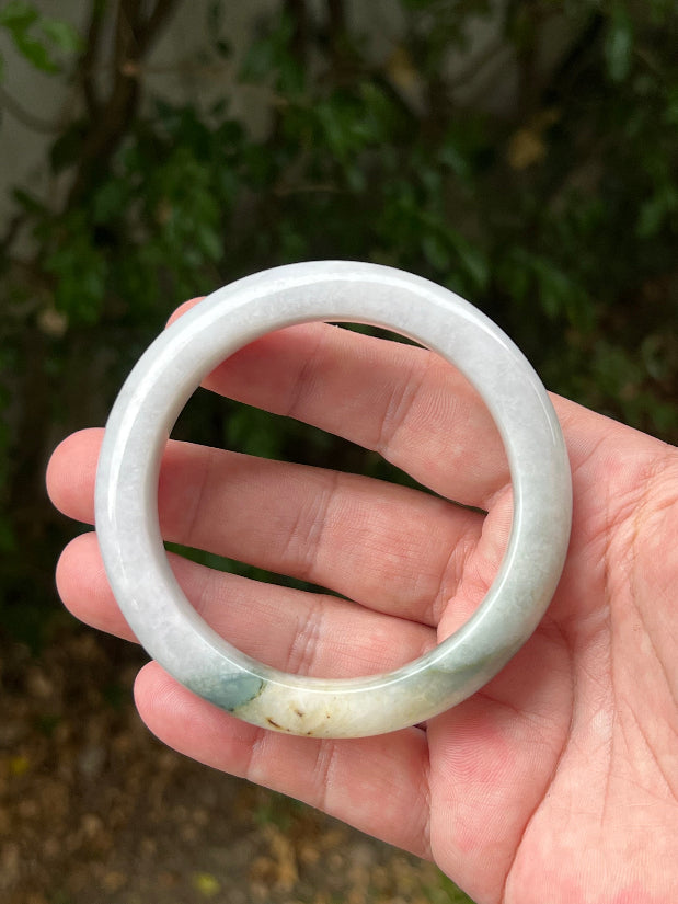 Close-up of soft green and honey patterns on icy white jadeite bangle