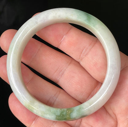 Hand holding a 56.8mm certified Grade A Burmese jadeite bangle in icy milky white and light lavender with apple and imperial green hues, item JB215