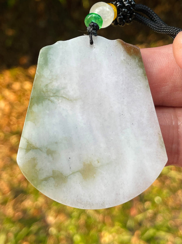 Untreated Type A Burmese jade pendant showing translucent luster with beautiful imperial green, white, and golden brown colors on an adjustable cord