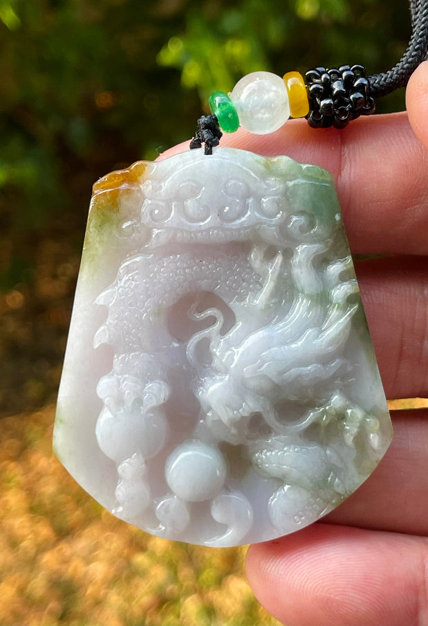 Untreated Type A Burmese jade pendant showing translucent luster with beautiful imperial green, white, and golden brown colors on an adjustable cord