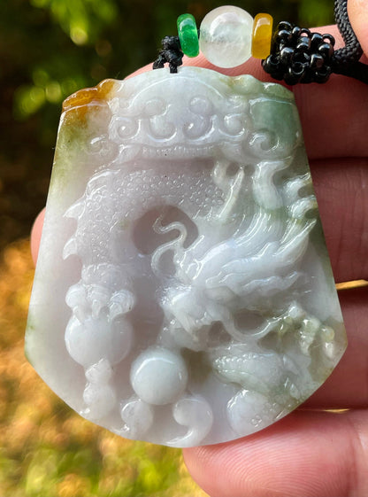 Untreated Type A Burmese jade pendant showing translucent luster with beautiful imperial green, white, and golden brown colors on an adjustable cord