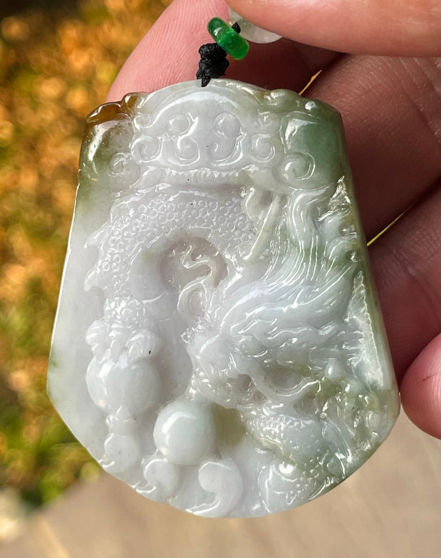 Untreated Type A Burmese jade pendant showing translucent luster with beautiful imperial green, white, and golden brown colors on an adjustable cord