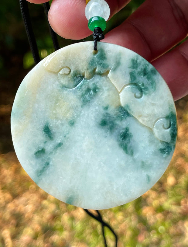 Untreated Type A Burmese jade pendant showing translucent luster with beautiful imperial green and white colors on an adjustable cord