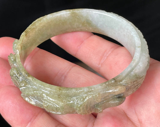 Close-up of a 58.9mm certified natural Grade A Burmese jadeite bangle featuring icy apple and forest green hues with a hand-carved dragon motif, item JB208