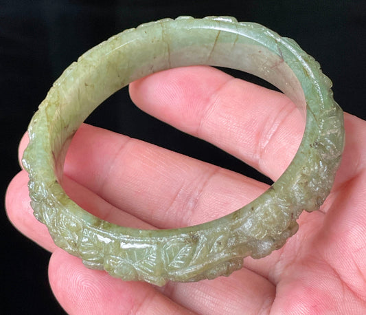 Close-up of a 58.3mm certified natural Grade A Burmese jadeite bangle featuring icy apple green hues and hand-carved floral motifs, item JB211