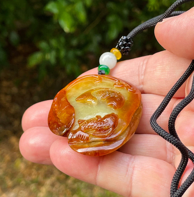 Untreated Type A Burmese jade pendant showing translucent luster with beautiful earthy orange and green colors on an adjustable cord