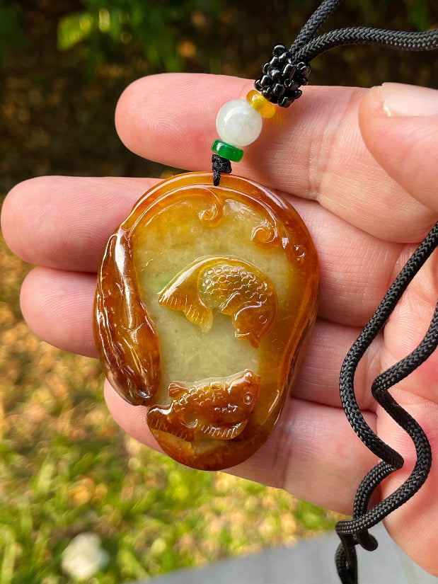 Untreated Type A Burmese jade pendant showing translucent luster with beautiful earthy orange and green colors on an adjustable cord