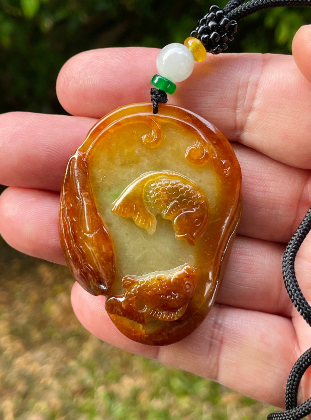 Untreated Type A Burmese jade pendant showing translucent luster with beautiful earthy orange and green colors on an adjustable cord
