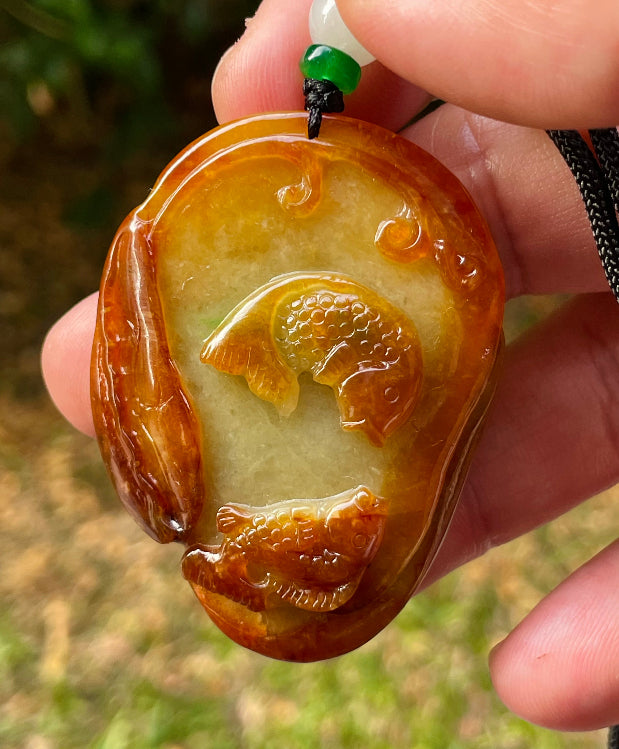 Untreated Type A Burmese jade pendant showing translucent luster with beautiful earthy orange and green colors on an adjustable cord