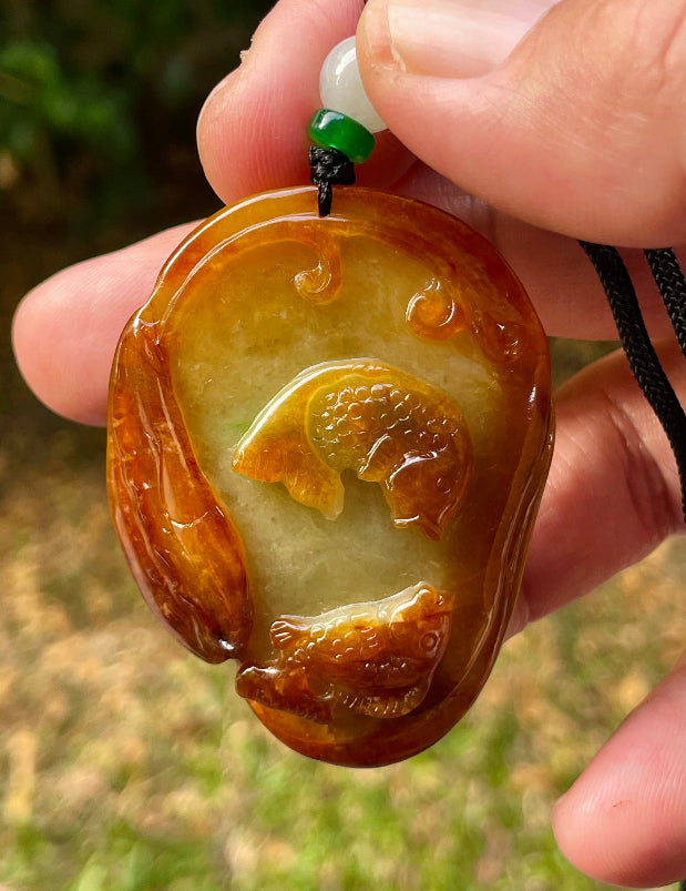 Untreated Type A Burmese jade pendant showing translucent luster with beautiful earthy orange and green colors on an adjustable cord