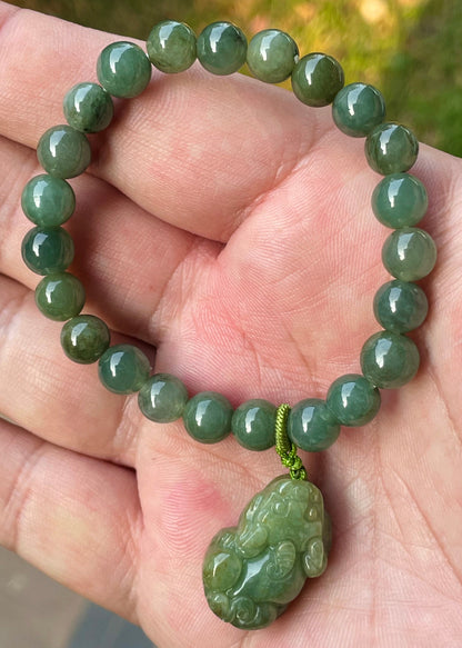 7mm natural Type A Burmese jade beads showing gentle translucency, deep apple green hues, and a hand-carved Pixiu pendant on the wrist